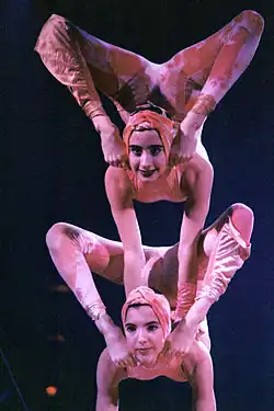 A female acrobat balancing on top of another.
