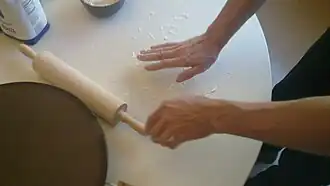 Putting flour on a flat table, in preparation for rolling out the dough.
